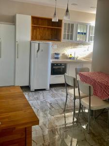 a kitchen with a table and a white refrigerator at Flat Próximo Shopping Santa Úrsula in Ribeirão Preto