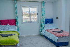a bedroom with two beds and a window at Appartement Laaz in Midelt