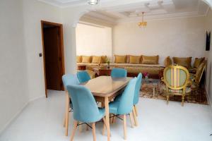 a dining room with a table and blue chairs at Appartement Laaz in Midelt