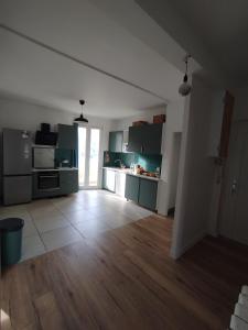 a large kitchen with green cabinets and a wooden floor at Chambre Privée Quokka Room in Longeville-lès-Metz