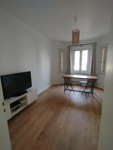 a living room with a table and a television at Chambre Privée Quokka Room in Longeville-lès-Metz