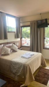 a bedroom with a large bed and two windows at Pousada Arco Iris in Gonçalves