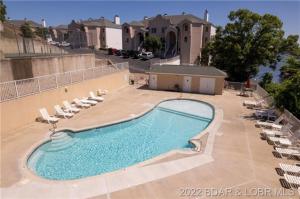 a large swimming pool with chairs and a building at Upscale Condo, Amazing Views, Pools and Pickleball in Lake Ozark