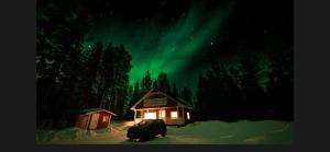 a car parked in front of a cabin under the northern lights at Velhonkieppi in Kittilä