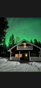 a house in the snow with a green sky at Velhonkieppi in Kittilä