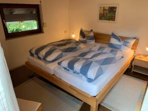 a bed with blue and white sheets and a window at Ferienhaus Bausch in Balderschwang