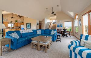 a living room with blue couches and a table at Climate Change - Duck, Sea Tern, Oceanside, 280 Yds to Beach, Pool, Hot Tub, Pets OK in Duck