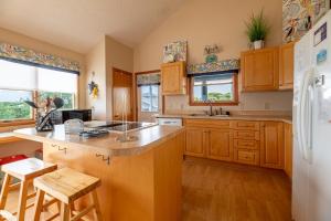 a kitchen with wooden cabinets and a white refrigerator at Climate Change - Duck, Sea Tern, Oceanside, 280 Yds to Beach, Pool, Hot Tub, Pets OK in Duck
