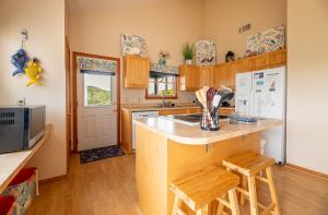 a kitchen with a sink and a counter with stools at Climate Change - Duck, Sea Tern, Oceanside, 280 Yds to Beach, Pool, Hot Tub, Pets OK in Duck