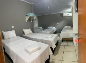 ein Krankenzimmer mit drei Betten mit weißen Laken in der Unterkunft Alfa Hotel in Nerópolis