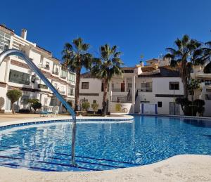 a large swimming pool with palm trees and buildings at Caballito del Mar apartment in Punta Prima