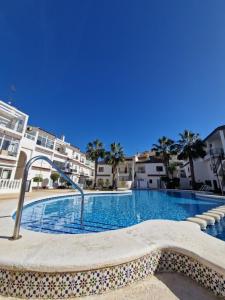 a large swimming pool with palm trees and buildings at Caballito del Mar apartment in Punta Prima