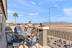 a family sitting at a table on the balcony of a house at Sleeps 14 Pool Fire Pit Billiards EV Plug in Mesa