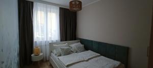 a bedroom with a white bed with a window at APARTAMENT RELAX in Ełk