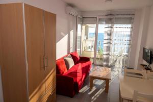 a living room with a red couch and a table at Roxhensi Apartments in Shëngjin