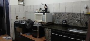a small kitchen with a microwave and a stove at Casa no Centro de Piracicaba - SP in Piracicaba