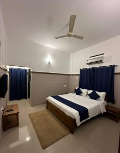 a bedroom with a large bed with blue curtains at The Rosetta Inn, Wayanad in Wayanad