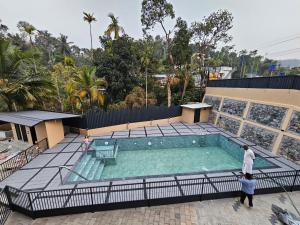 a swimming pool with two people standing around it at The Rosetta Inn, Wayanad in Wayanad
