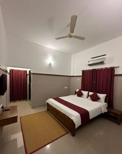 a bedroom with a large bed with red curtains at The Rosetta Inn, Wayanad in Wayanad +12 photos