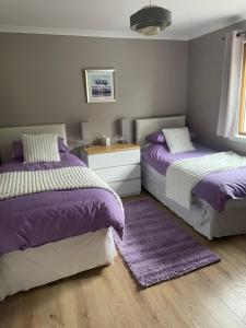 two beds in a bedroom with purple and white at Fraoch, Pets welcome in Port Bannatyne
