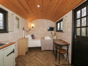 a small room with a bed and a table at Aston - Shepherd Hut in Craven Arms