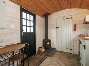 a room with a stove and a table and a door at Aston - Shepherd Hut in Craven Arms +14 photos