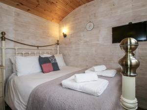 a bedroom with a bed with white sheets and a tv at Aston - Shepherd Hut in Craven Arms