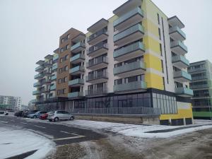 an apartment building with cars parked in a parking lot at Cazare Rasnov cu vedere spre Postavaru in Râşnov
