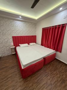 a red bed in a room with a red curtain at Cutesy space in Kolkata