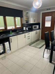 a kitchen with white cabinets and black counter tops at Fraoch, Pets welcome in Port Bannatyne