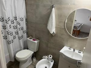 a bathroom with a toilet and a sink and a mirror at Departamento temporal in Morón