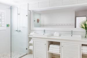 a white bathroom with two sinks and a shower at Couples Sans Souci in Ocho Rios