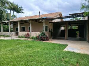 a house with a garage and a grass yard at Casa de Campo com piscina in Mairinque