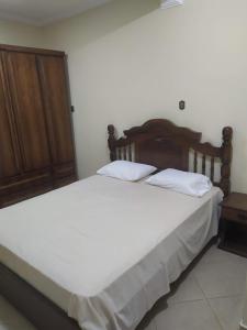 a bedroom with a large white bed with a wooden headboard at Casa de Campo com piscina in Mairinque +18 photos