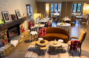 a restaurant with a couch and tables and a fireplace at Relais Manderen in Manderen
