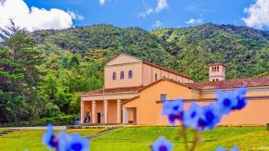 a large yellow building with a mountain in the background at La Jaus by Hope in Guatapé