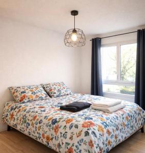 a bedroom with a bed with a floral comforter and a window at Les Logis de Paray - App 224 in Paray-le-Monial