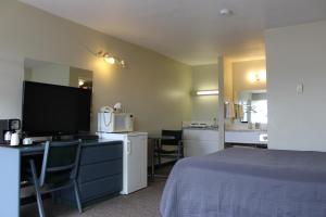 a hotel room with a bed and a desk with a computer at Plains Motor Inn in Stettler