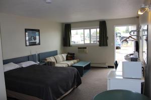 a bedroom with a bed and a couch and a table at Plains Motor Inn in Stettler