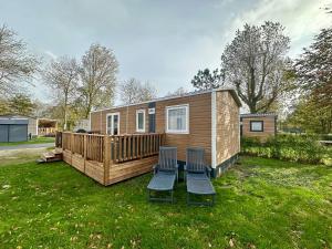 a tiny house with two chairs in a yard at Chalet Levy in Lauwersoog