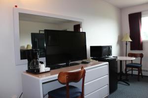 a hotel room with a desk with a large television at Plains Motor Inn in Stettler
