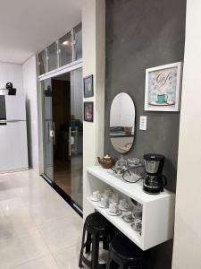 a room with a shelf with cups and a mirror at Casa em Dunas de Marapé -Jequia da praia in Jequia da Praia
