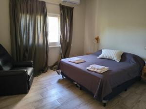 a bedroom with a bed and a chair and a window at Lisboa in Chacabuco