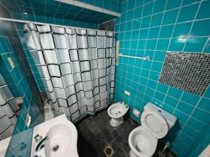a blue tiled bathroom with a toilet and a sink at Lisboa in Chacabuco
