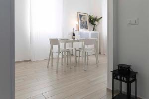 a dining room with a white table and chairs at ROSSENA HOME tranquillo appartamento, con giardino, vicino al centro ed all'Ospedale Santa Maria Nuova SMN in Reggio Emilia
