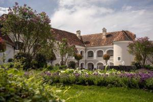 a large white house with a garden with purple flowers at Die Landhofmühle in Windisch Minihof