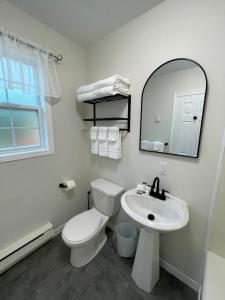 a white bathroom with a toilet and a sink at Buoy & Arrow Suites in Rocky Harbour +41 photos