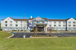 a large white building with a parking lot at Spark by Hilton Macon North in Macon