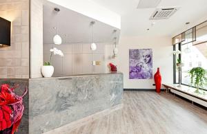 a lobby with a large marble counter and flowers at Leonardo Hotel Munich City North in Munich
