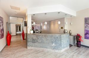 a lobby with a large mirror and red vases at Leonardo Hotel Munich City North in Munich